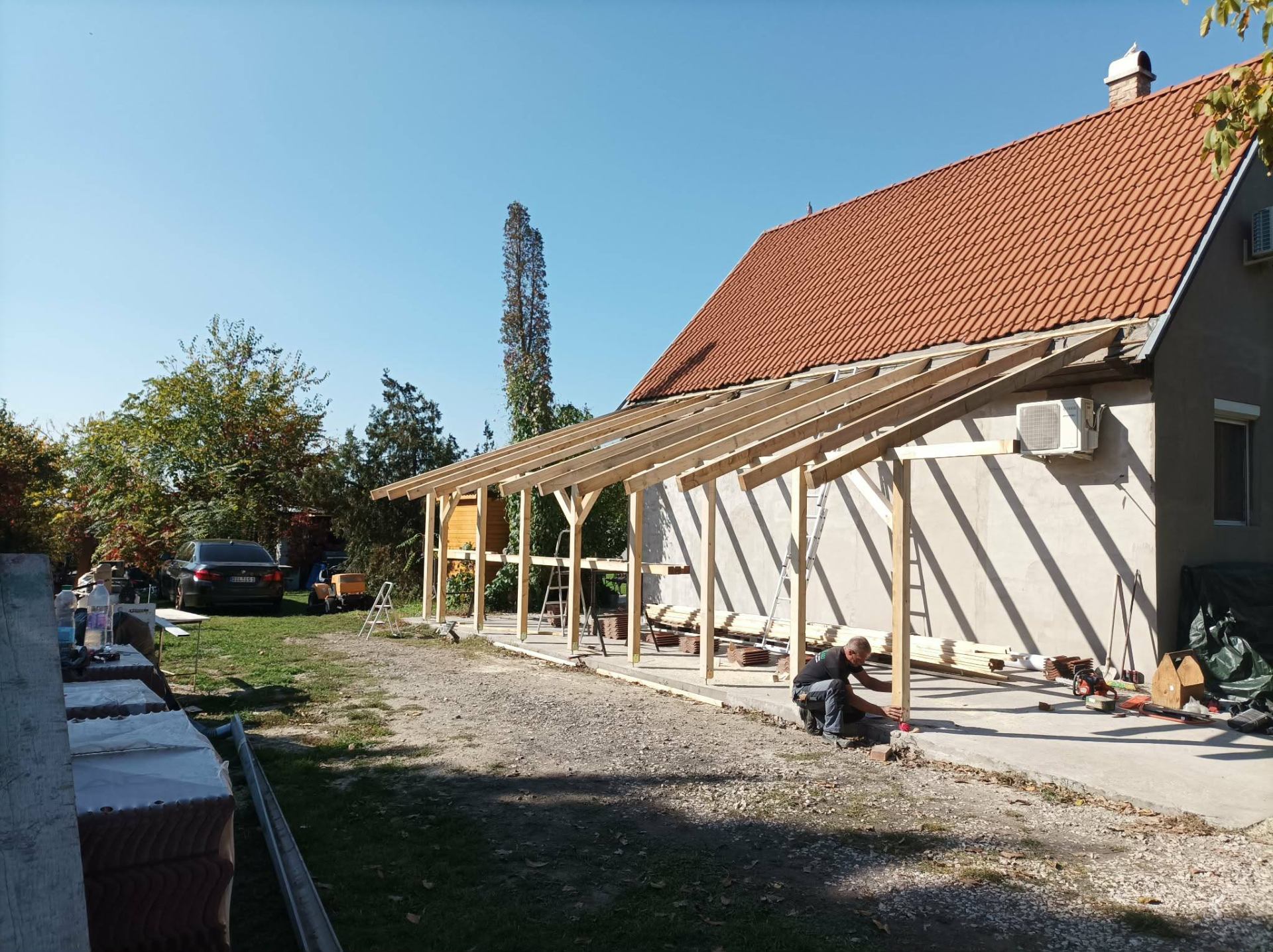 Faszerkezetes tartóoszlopok és gerendák felállítása a ház mellett